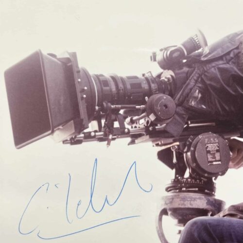 Portrait photographique de Claude Lelouch, jeune, derrière sa caméra, avec signature autographe