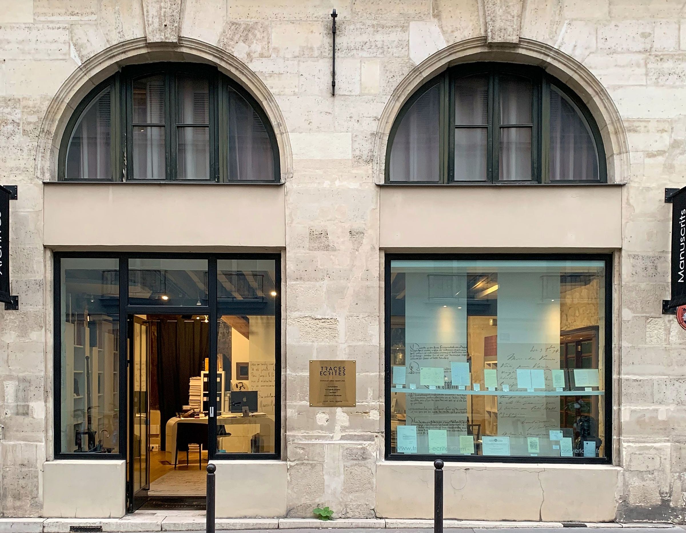 Façade de la librairie Traces Écrites, Paris (redressée, recadrée) Façade en pierre de la librairie Traces Écrites à Paris, fenêtres cintrées et vitrines
